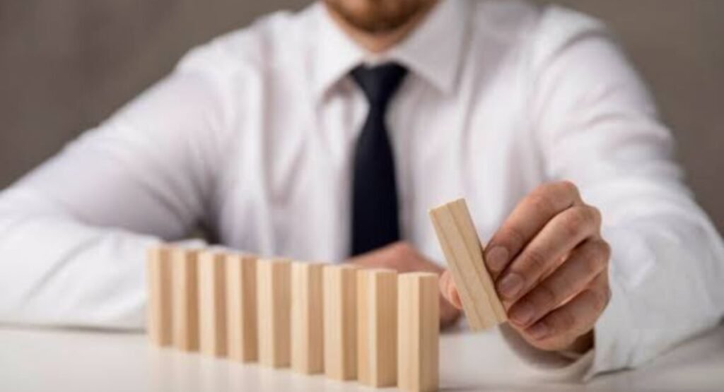 Businessman placing a wooden block to complete a line, representing risk management and strategy.